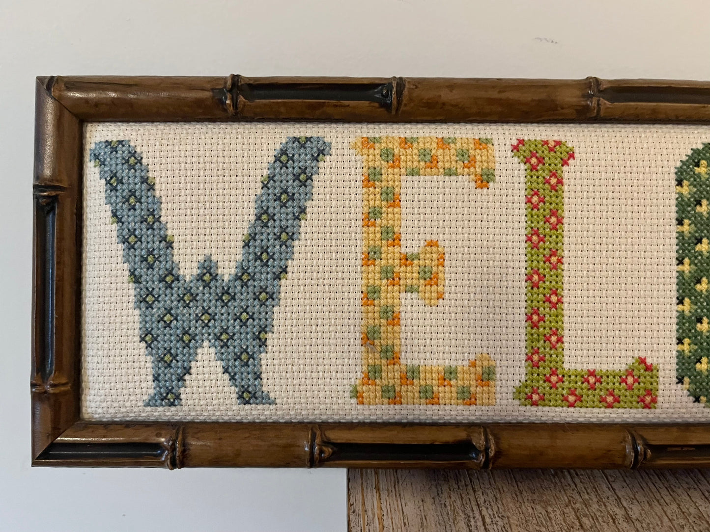 Close up of Vintage Needlepoint Welcome Sign with Wooden Bamboo Style Frame